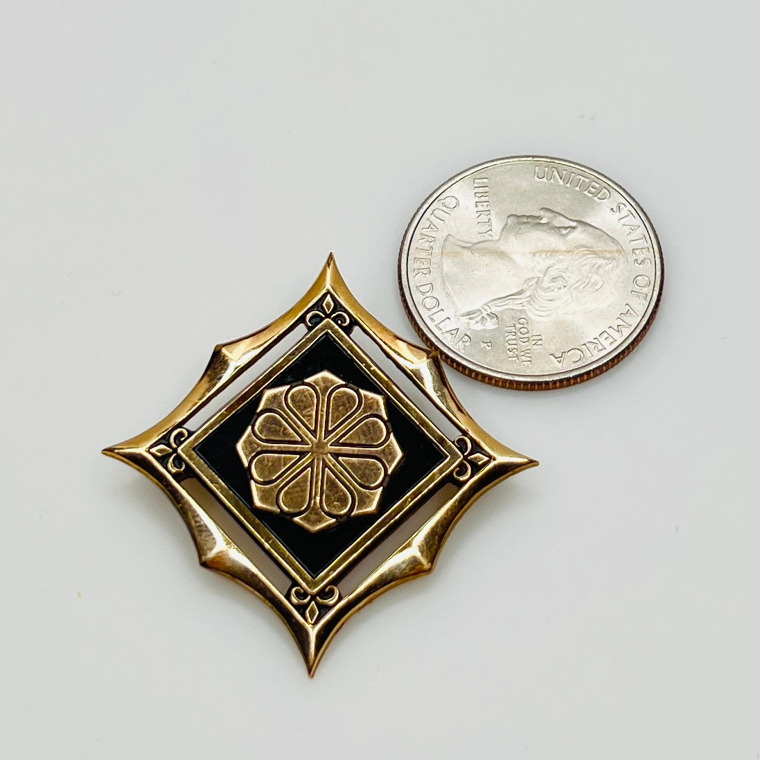 Vintage gold-filled enamel brooch shown next to a quarter for size reference