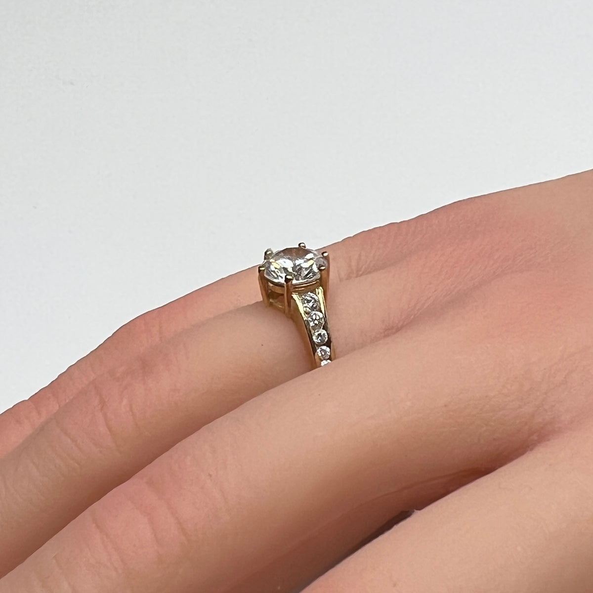 Vintage 10K gold CZ solitaire ring on hand with channel-set accents