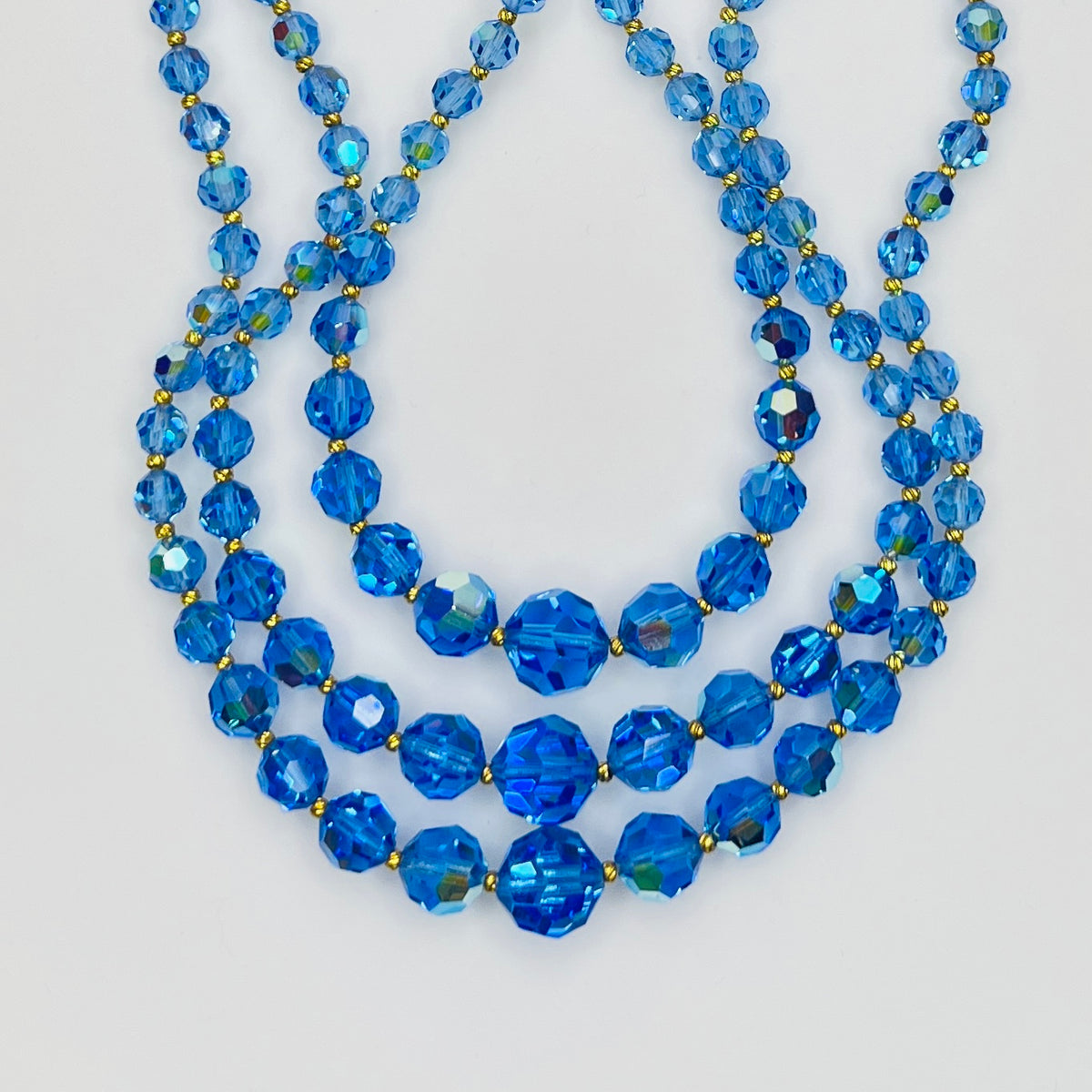 Close-up of graduated blue AB crystal beads with gold-tone spacers