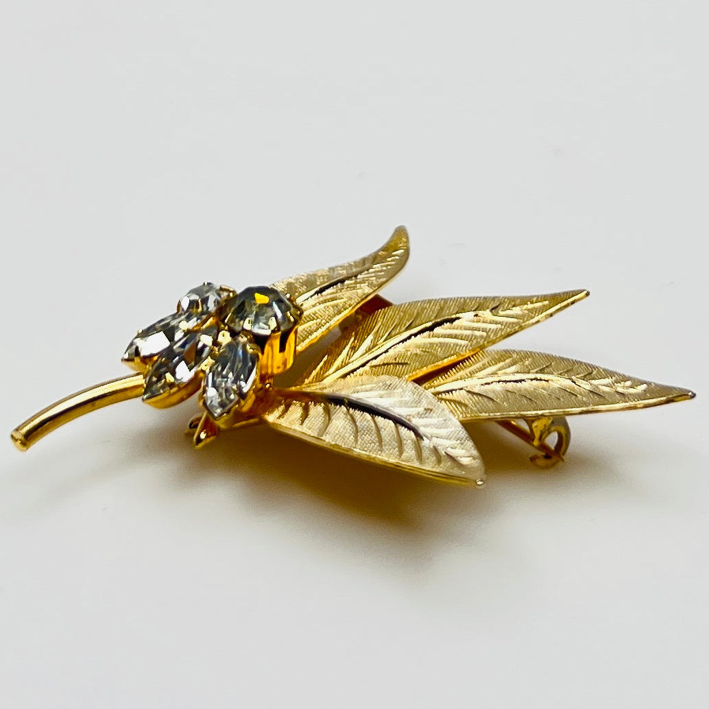 Close-up of gold-tone leaf brooch with clear rhinestones