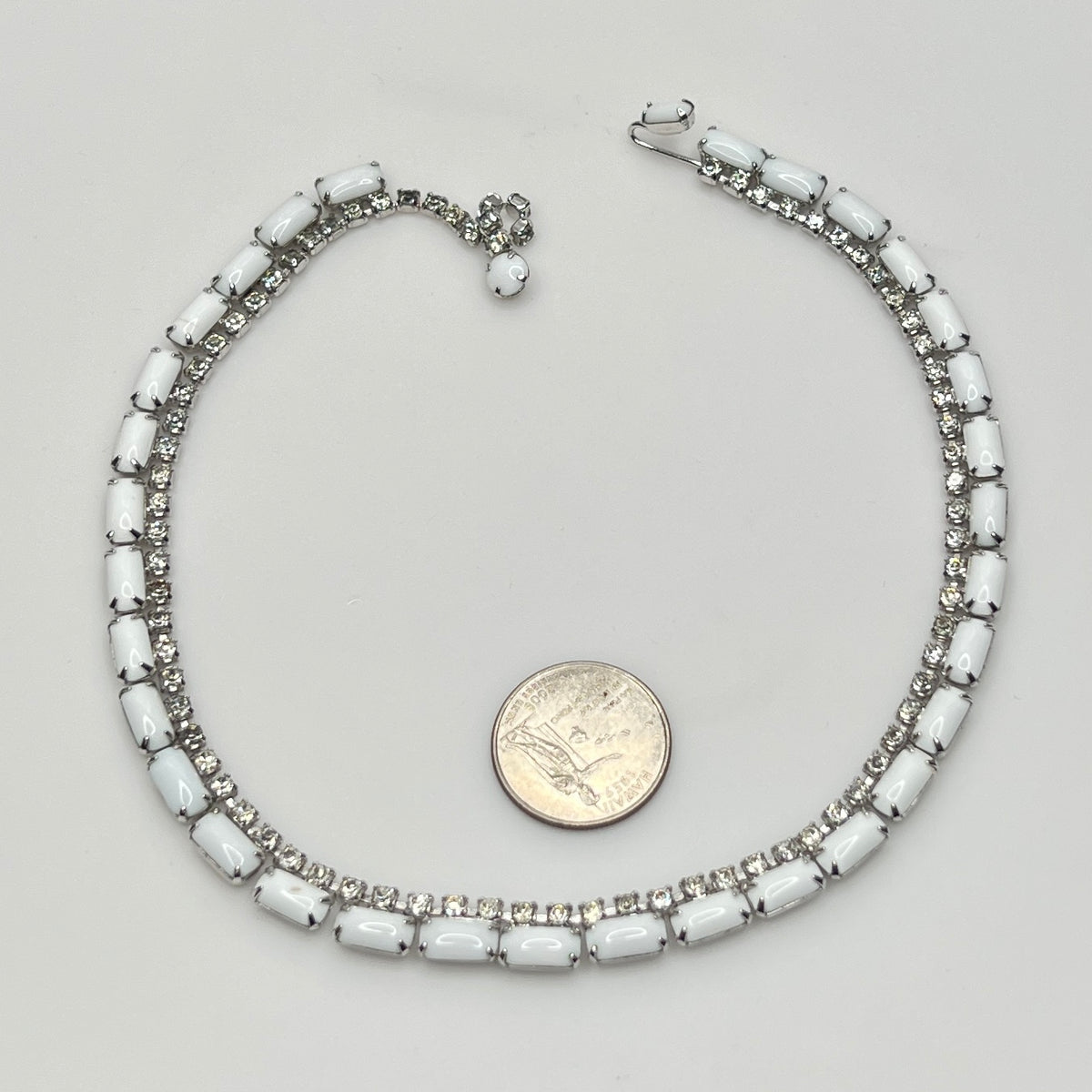 1950s milk glass and rhinestone choker necklace with silver-tone setting and hook closure.