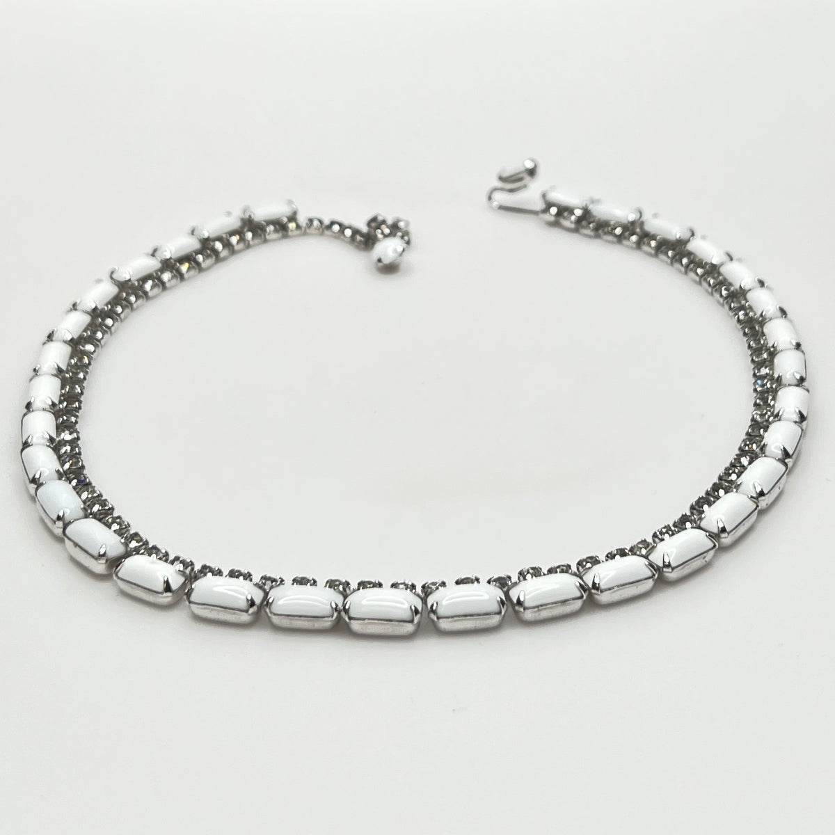 1950s milk glass and rhinestone choker necklace with silver-tone setting and hook closure.