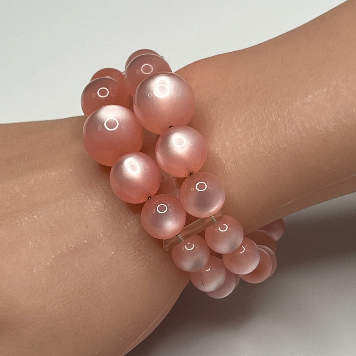 1950s pink moonglow lucite cuff bracelet on wrist, graduated round beads