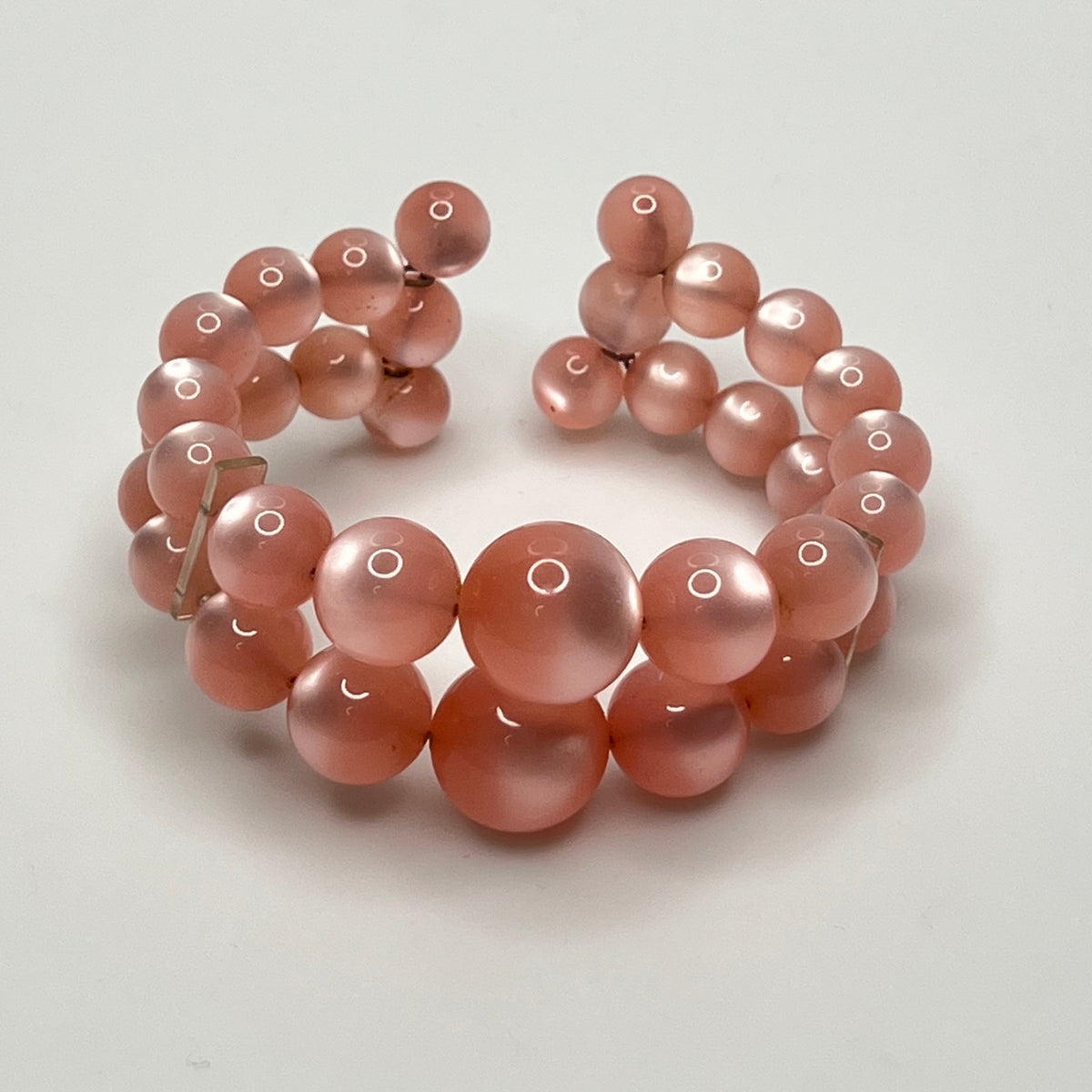Vintage pink lucite cuff bracelet in open wire design, glowing bead detail