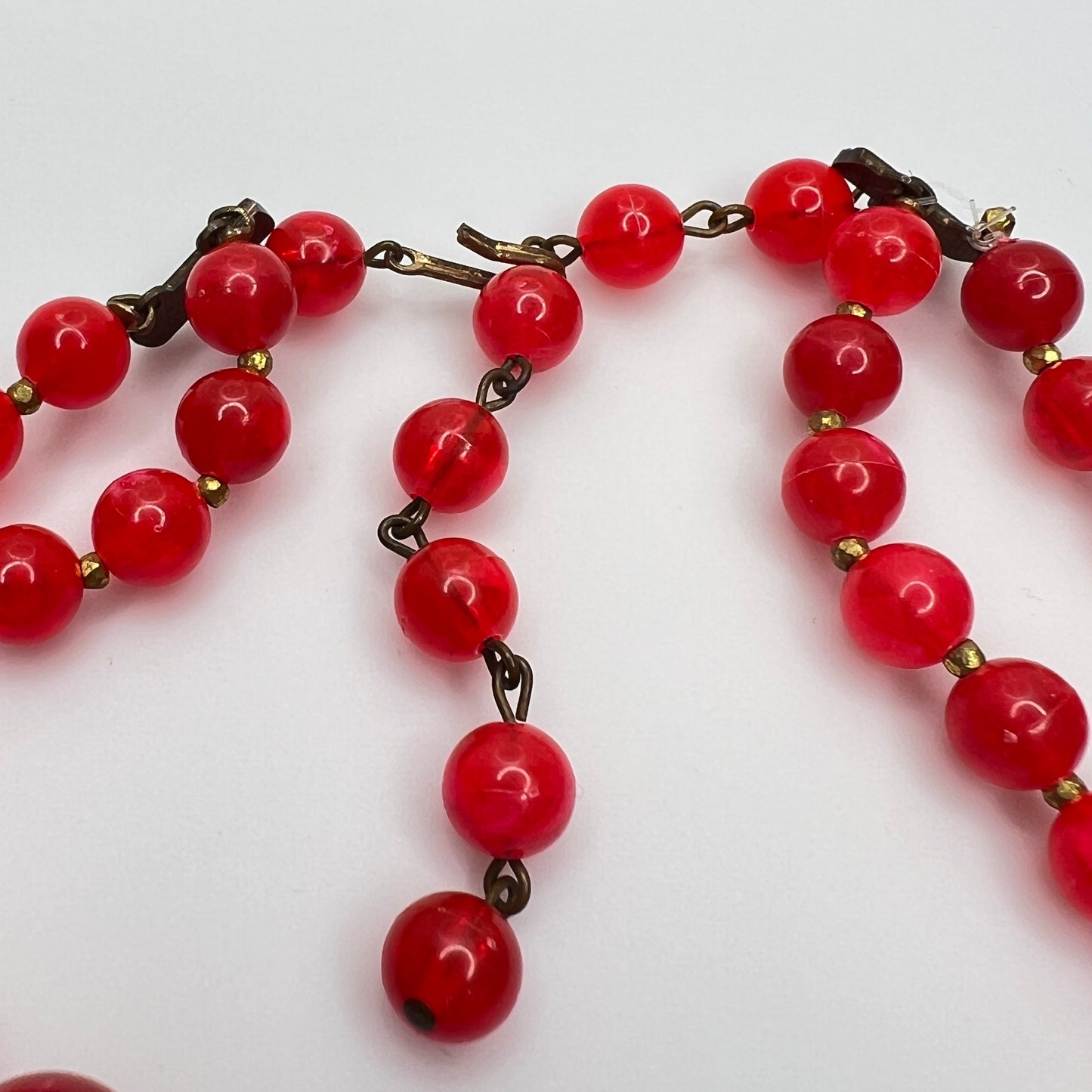Hook clasp of 1960s Red lucite beaded necklace on a white background