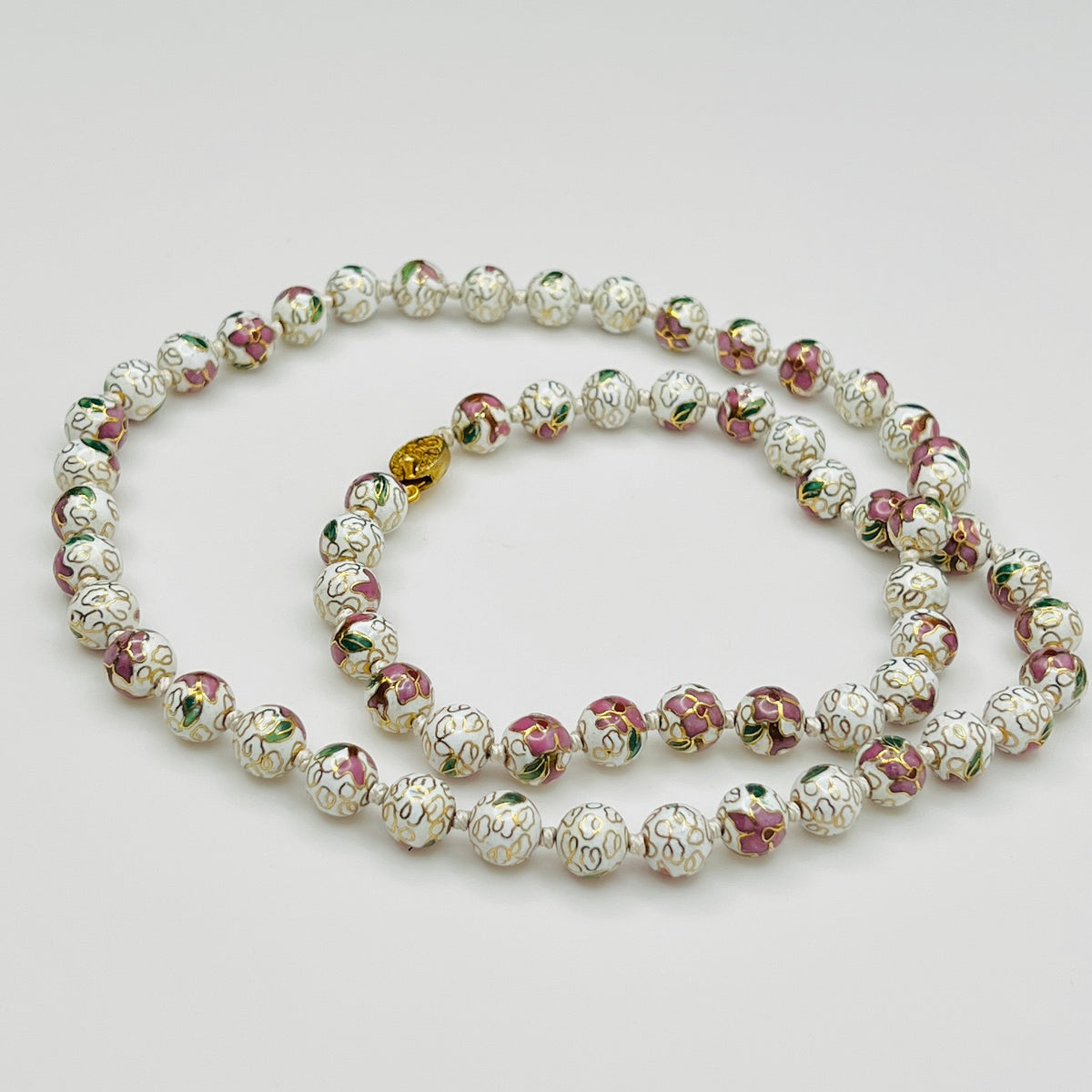 Close-up of plum and white floral enamel beads and box clasp