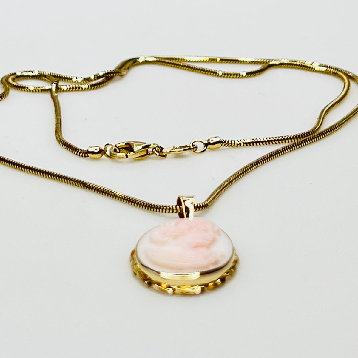 Close-up of oval pink cameo in 14K gold frame