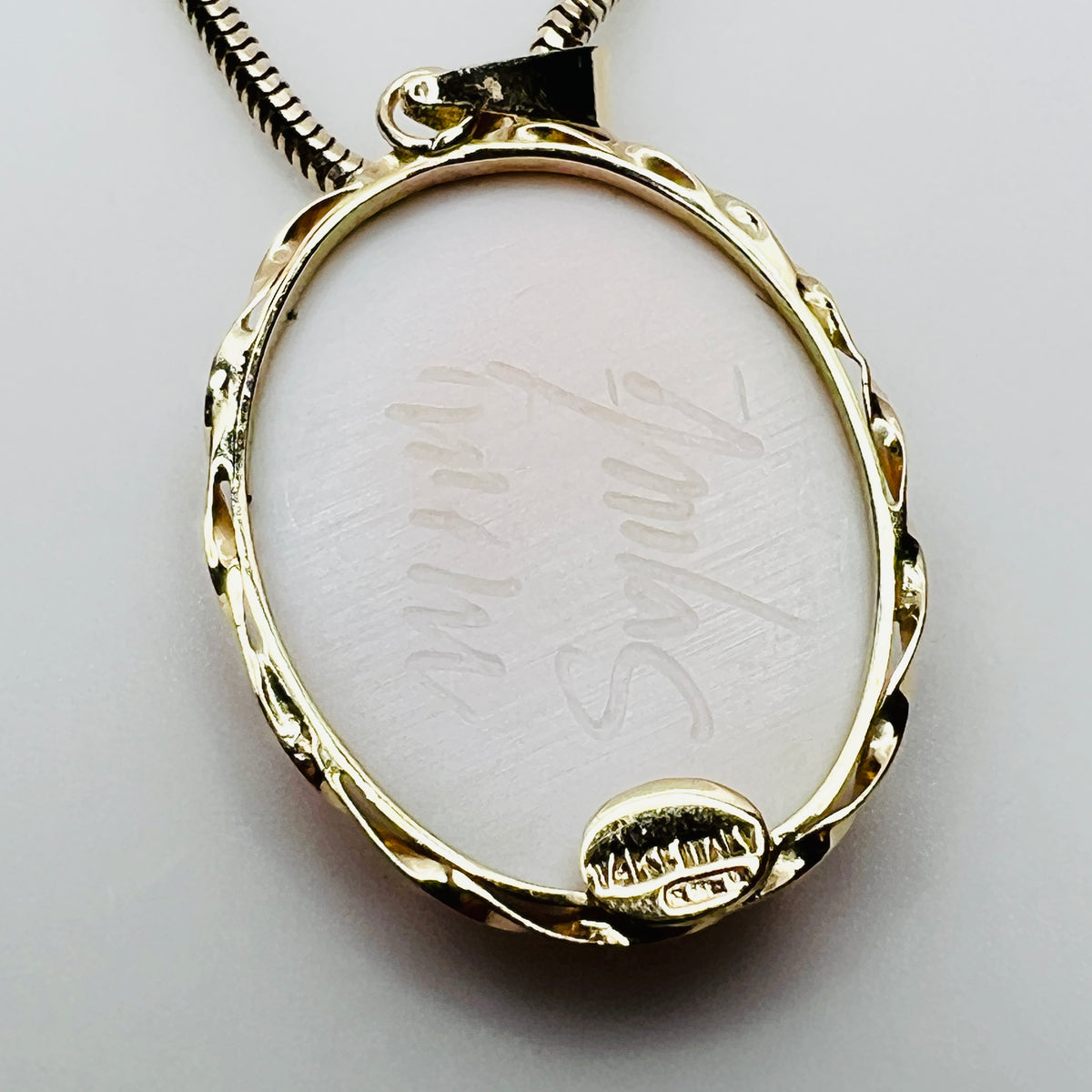 Back of cameo pendant showing artist signature and gold setting