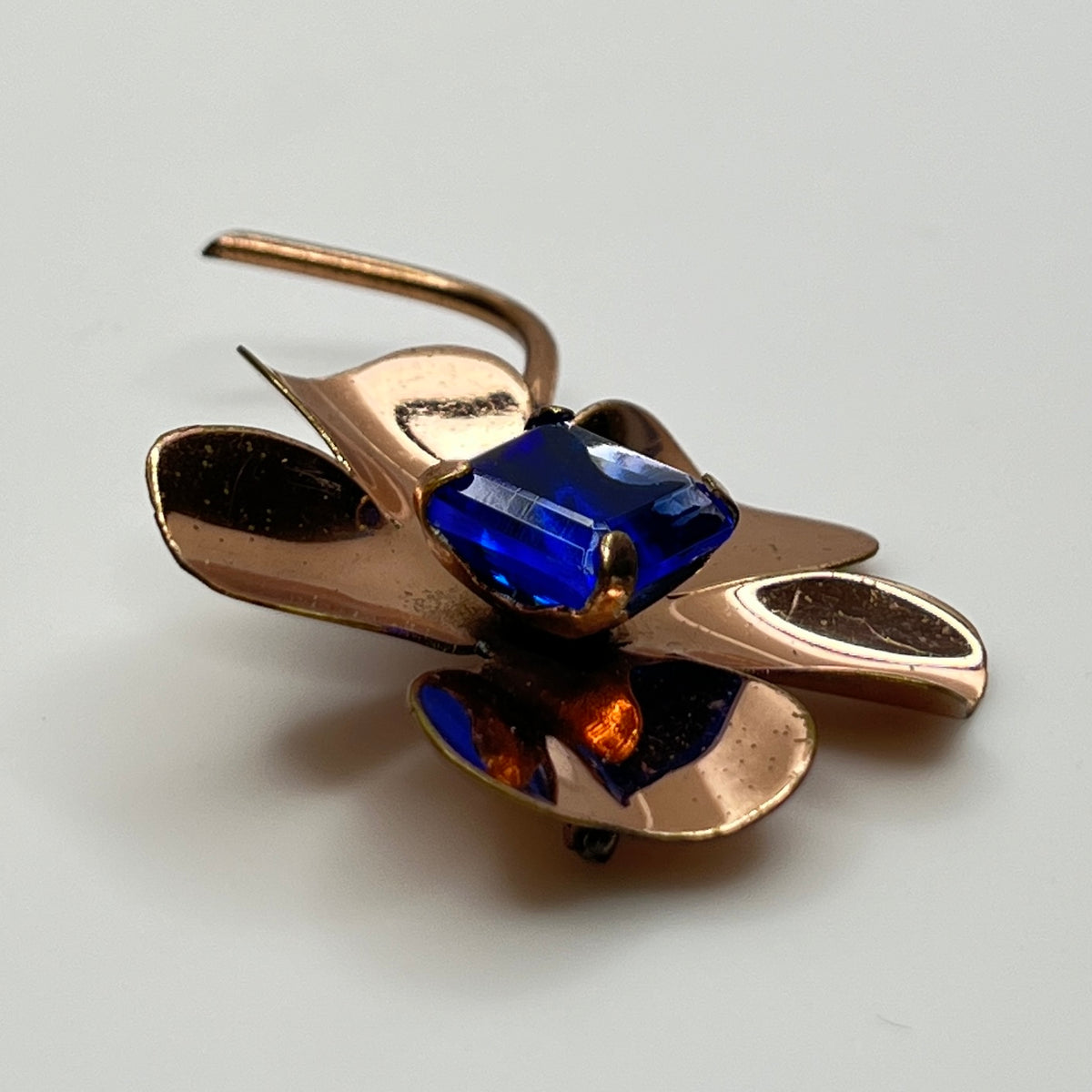 Copper-tone flower brooch with vivid cobalt blue glass rhinestone center