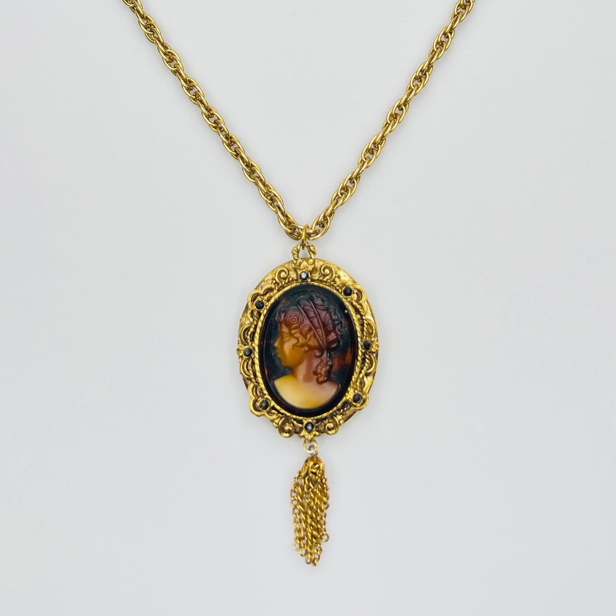 Gold tone glass cameo locket necklace with tassel drop