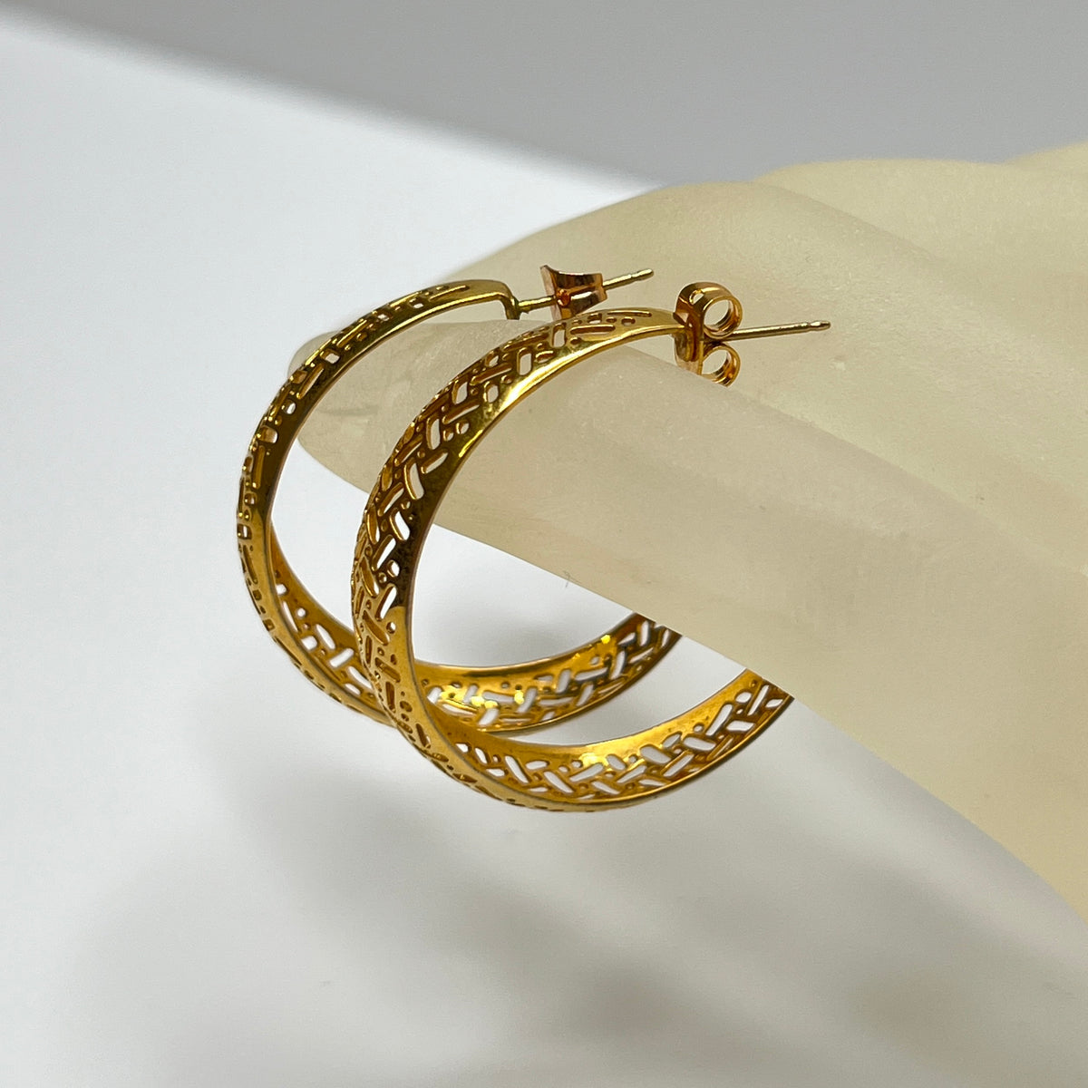 Domed gold-tone hoops with intricate lattice design, side view