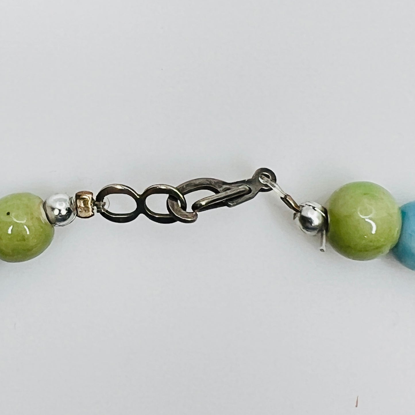 Flat lay of wood and ceramic bead necklace with close up of hook clasp