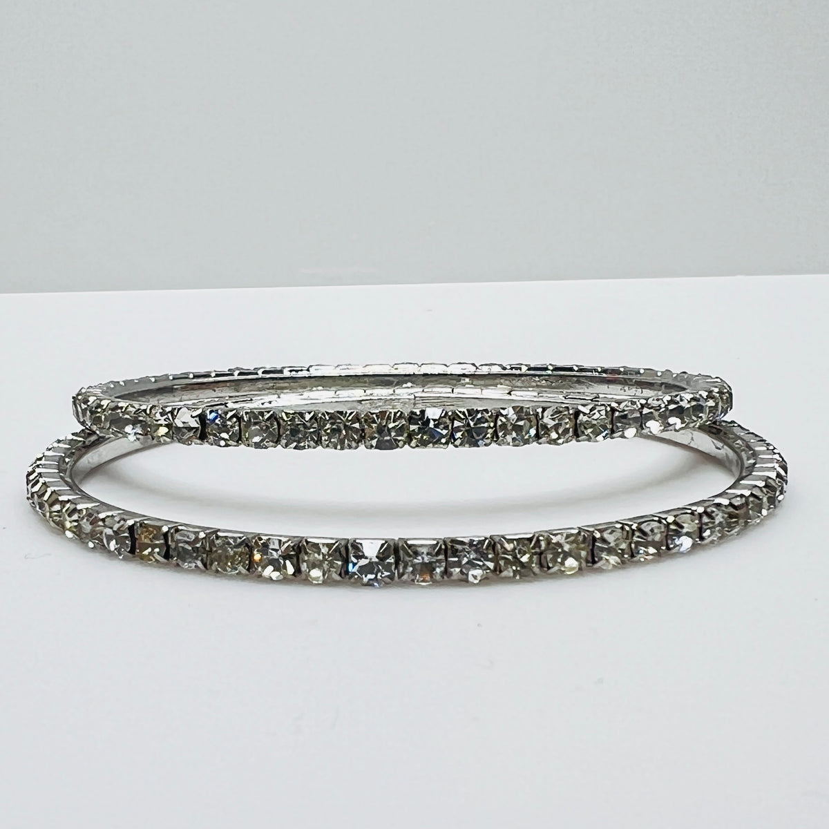 Set of two silver-tone bangle bracelets with prong-set clear rhinestones, vintage 1980s.