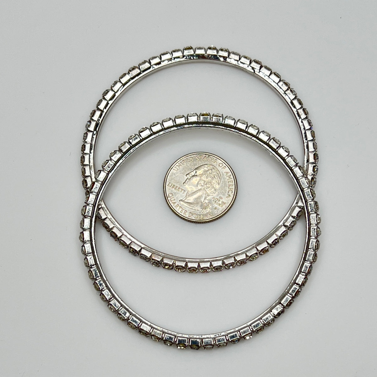 Set of two silver-tone bangle bracelets with prong-set clear rhinestones, vintage 1980s.
