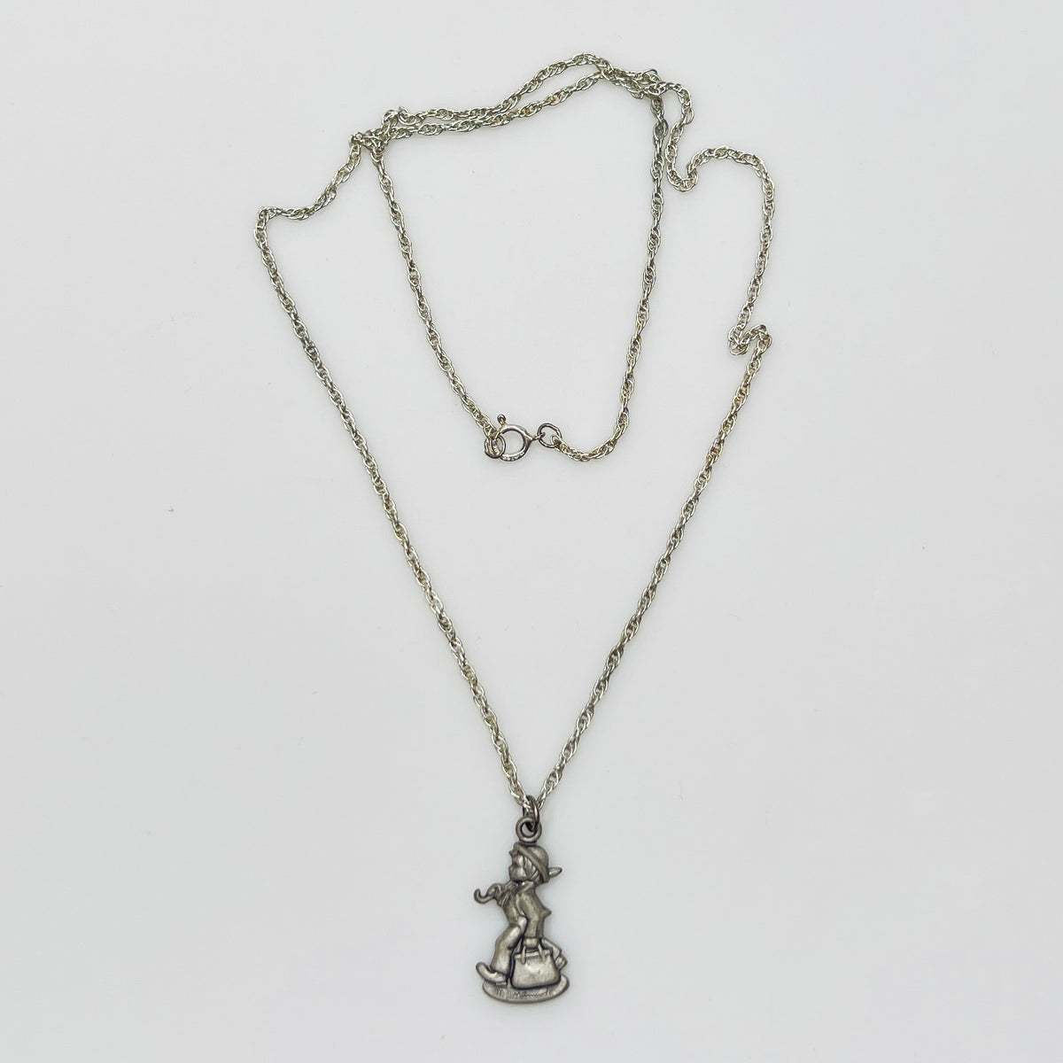 Flat lay of silver Hummel pendant necklace with twist chain