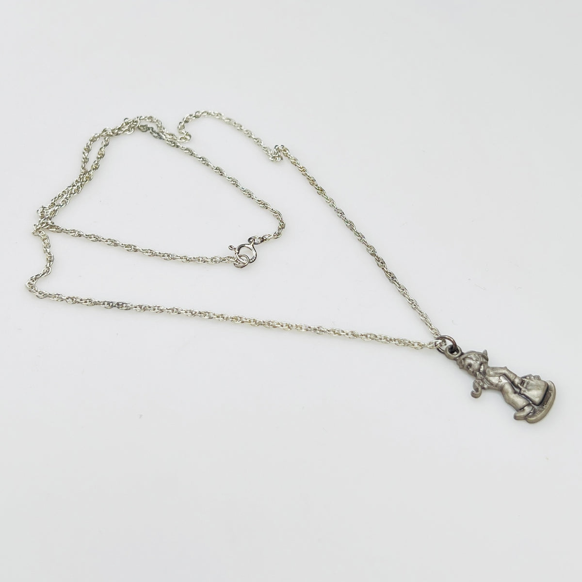 Side view Flat lay of silver Hummel pendant necklace with twist chain