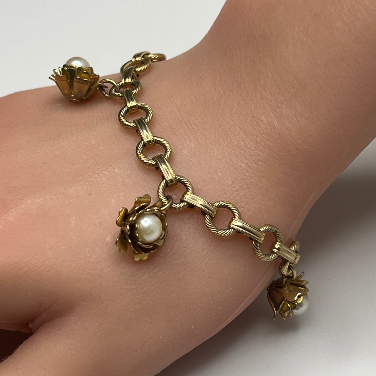 Feminine gold-tone bracelet with four pearl-in-bloom charms