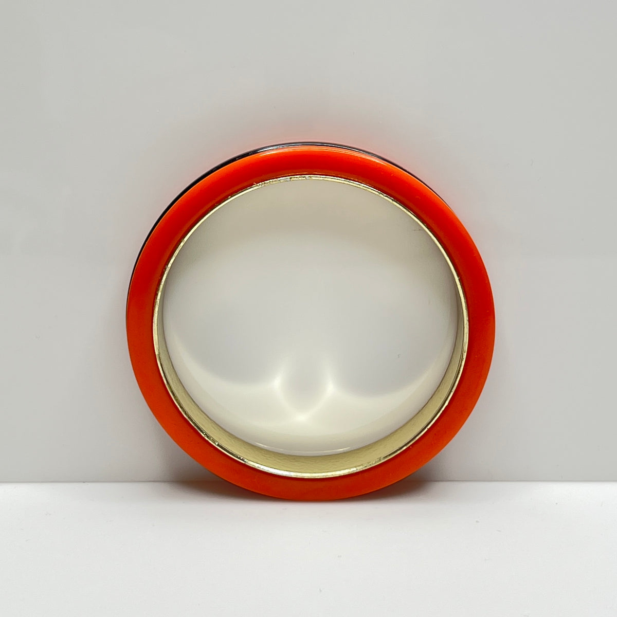 Orange Bakelite bangle bracelet with black stripe and gold-tone interior
