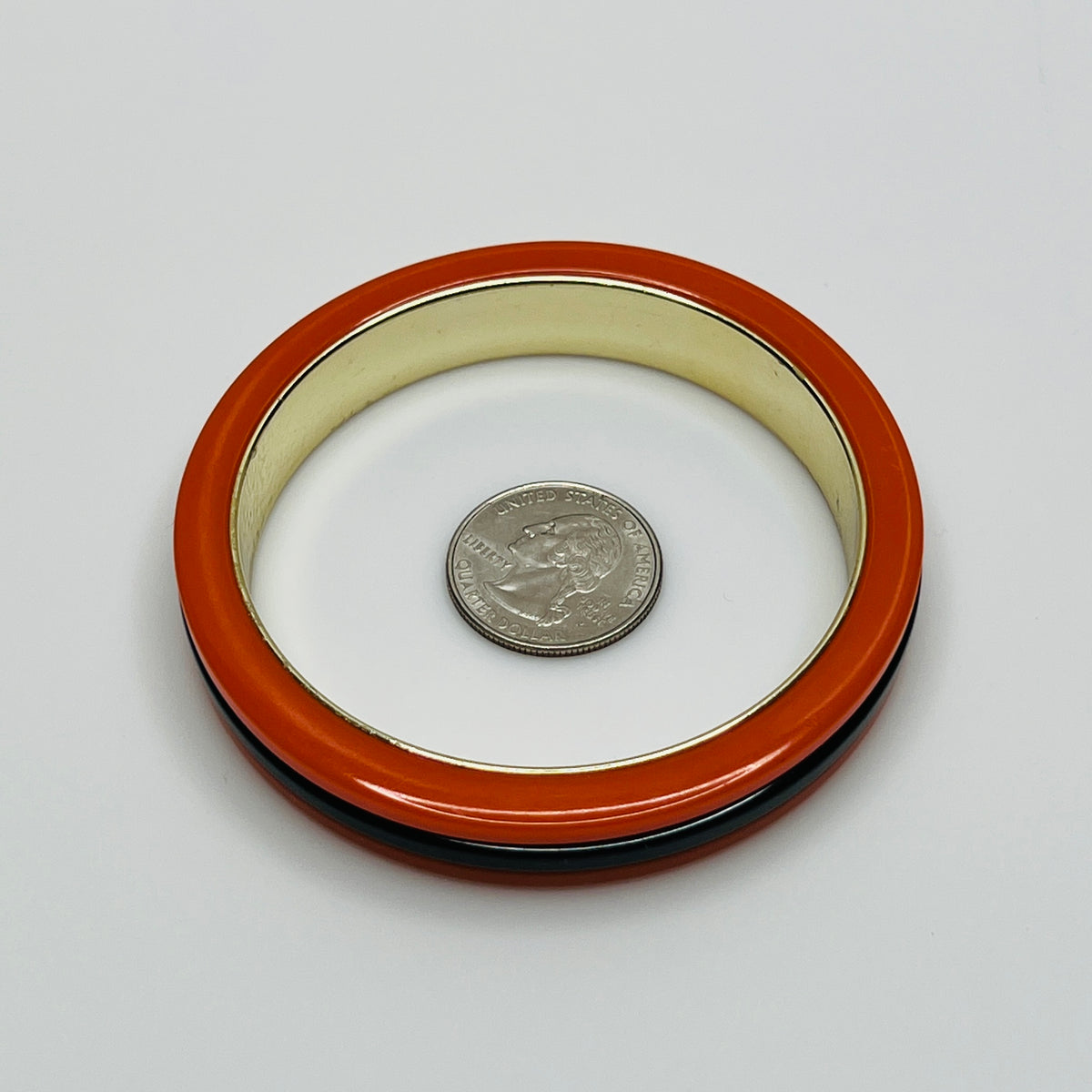 Orange Bakelite bangle bracelet with black stripe and gold-tone interior