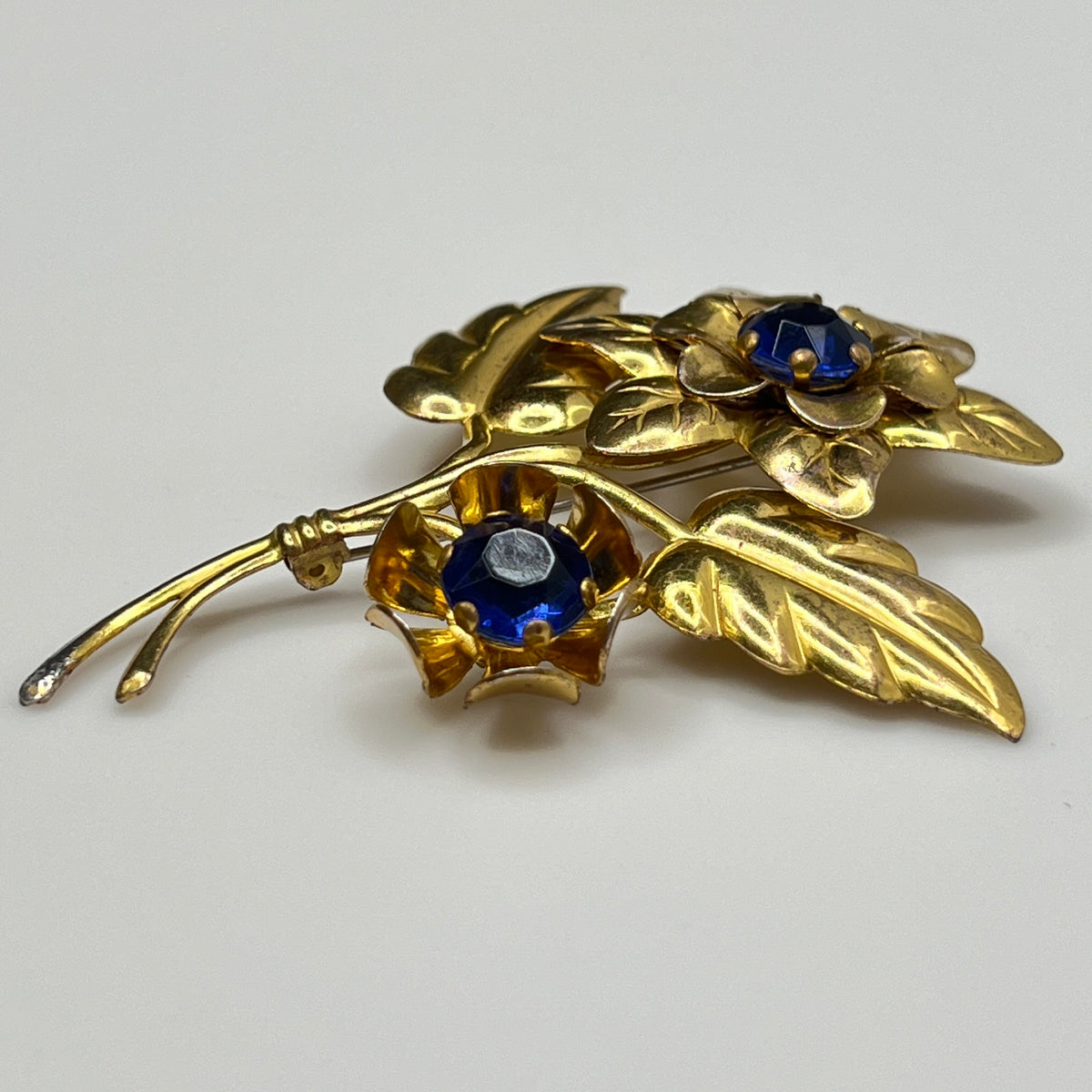 Gold brooch with blue gemstones on a white background