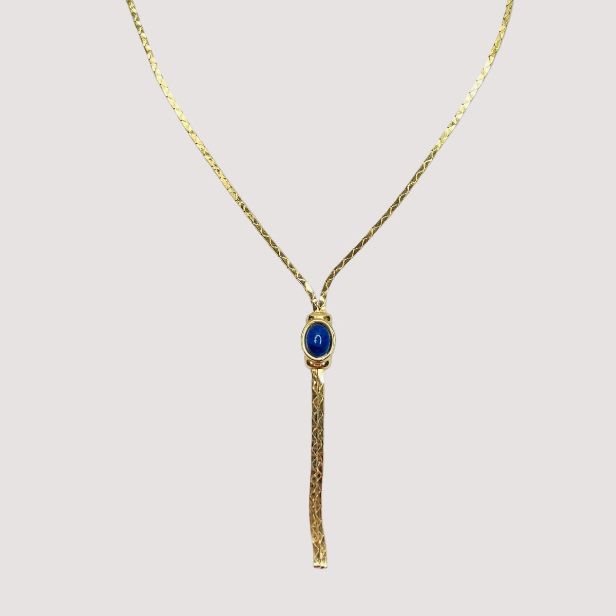 Full view of necklace with lariat drop and blue stone on white background