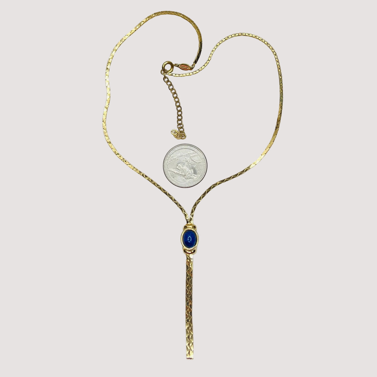 Full view of necklace with lariat drop and blue stone on white background