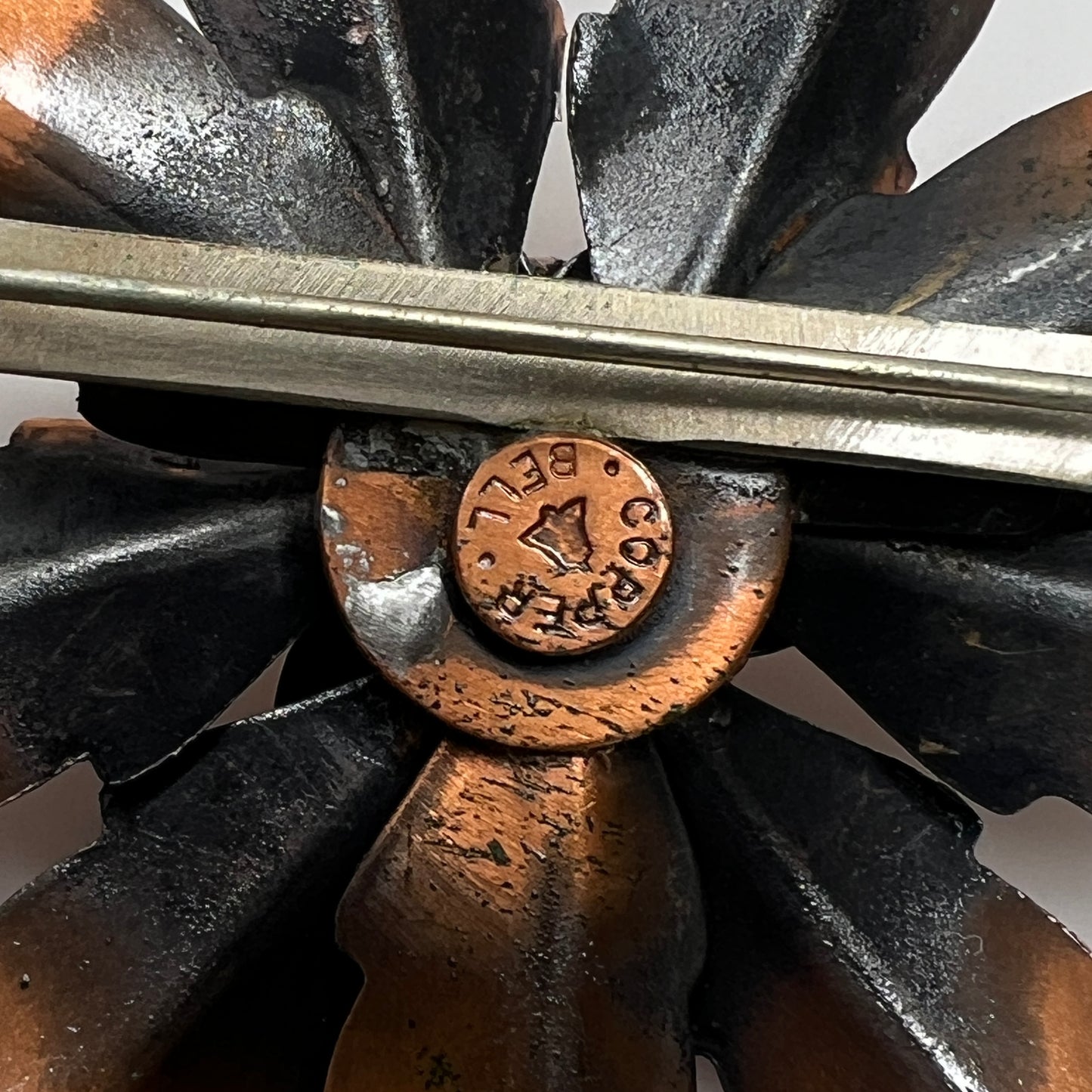 Reverse of copper brooch showing Copper Bell stamp and bell logo