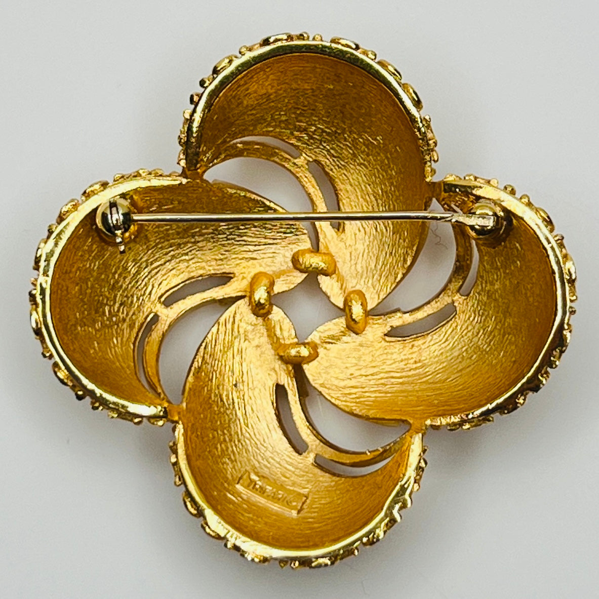 Back view Crown Trifari gold swirl brooch with clover-style textured domes