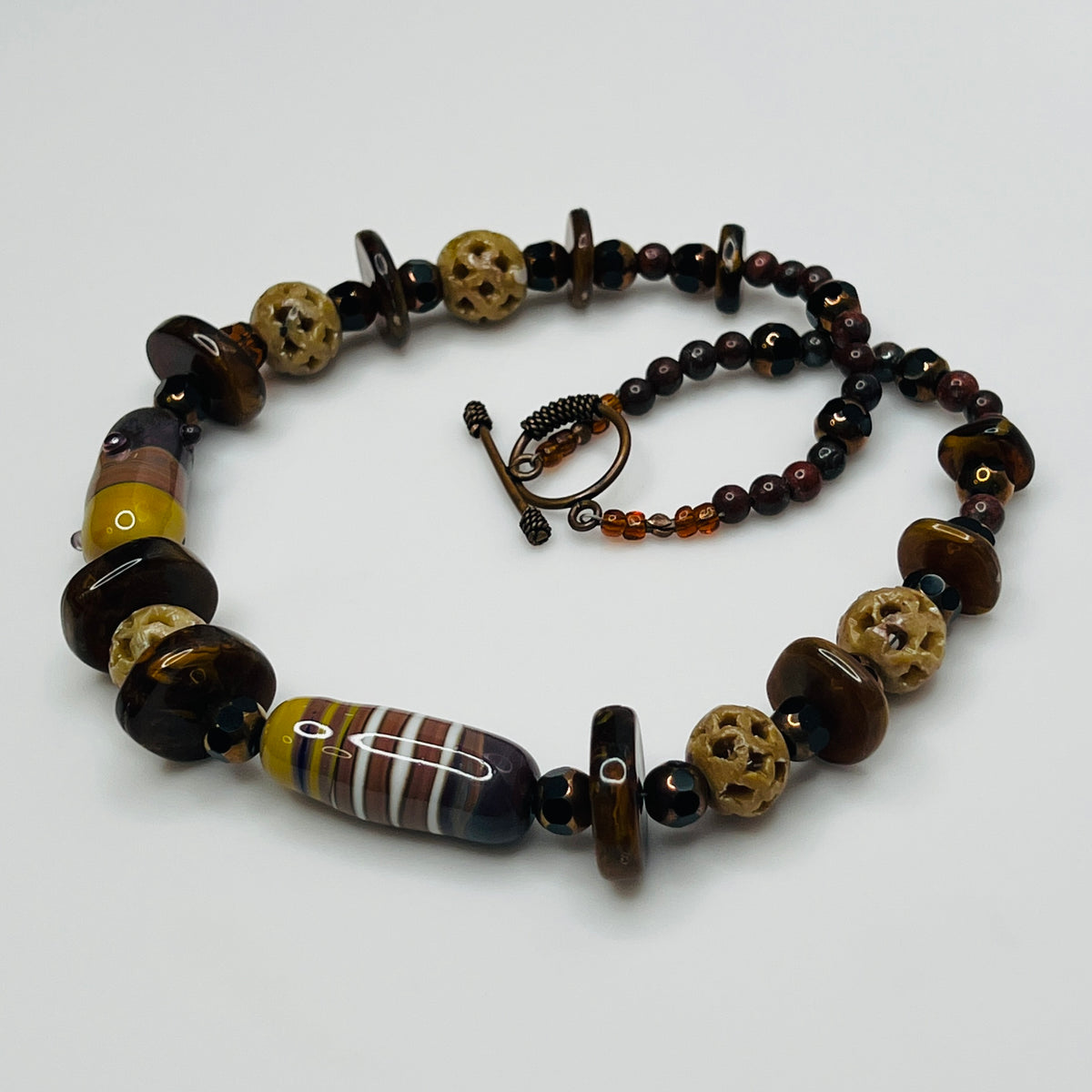 Vintage necklace with glass and carved stone beads in warm earthy tones