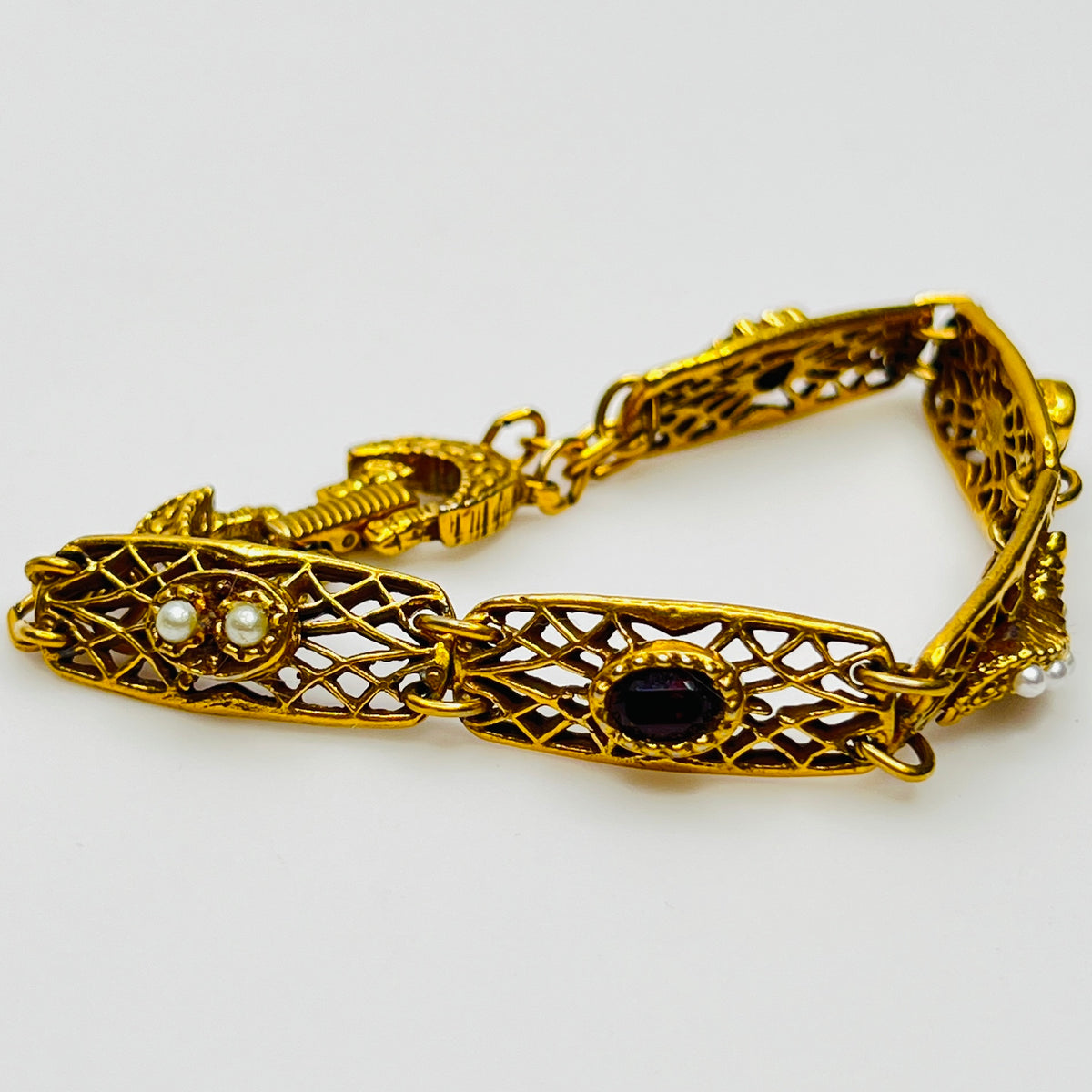 Filigree bracelet with varied gemstone details laid flat, fold-over clasp visible