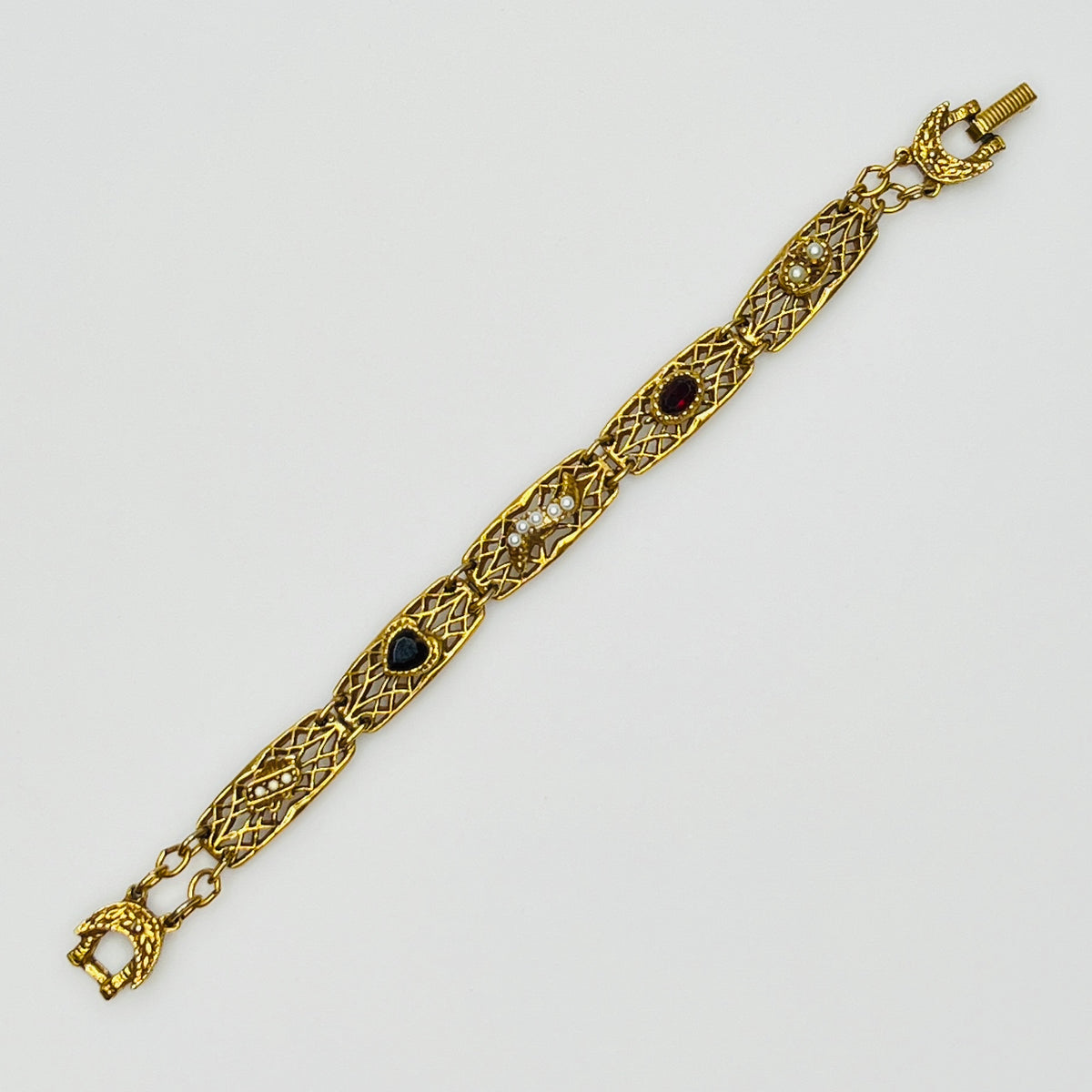 Filigree bracelet with varied gemstone details laid flat, fold-over clasp visible