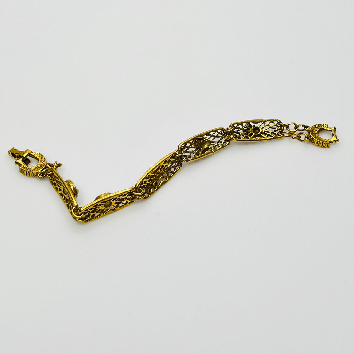 Filigree bracelet with varied gemstone details laid flat, fold-over clasp visible