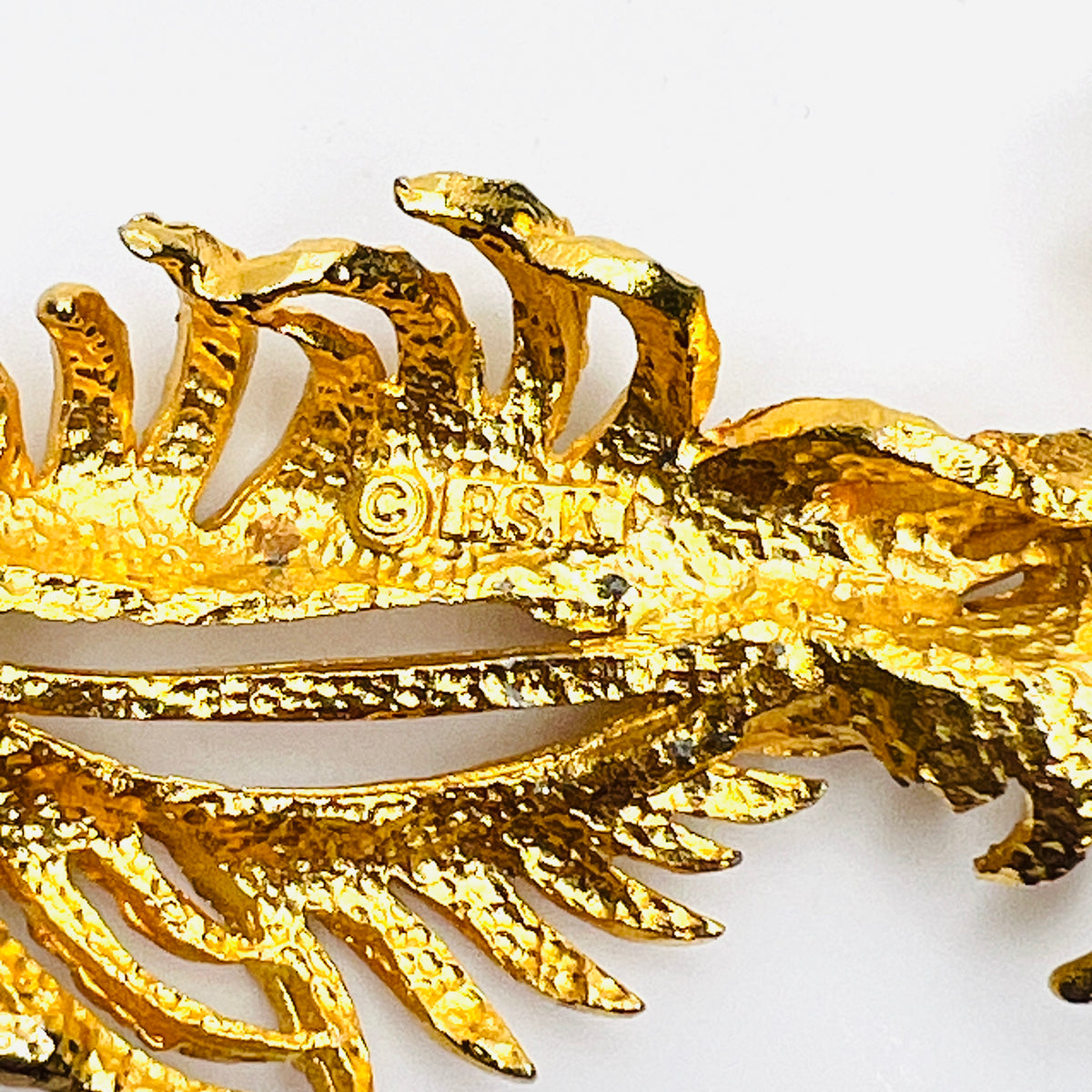 Close-up of BSK maker's signature and small area of finish wear on reverse of vintage botanical brooch