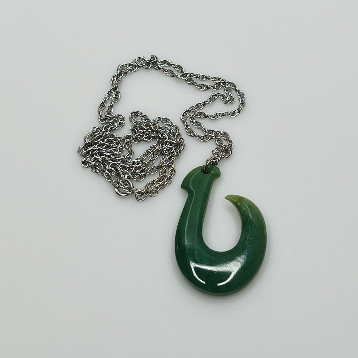 Close-up of green jade pendant with twisted white gold-tone chain and spring clasp
