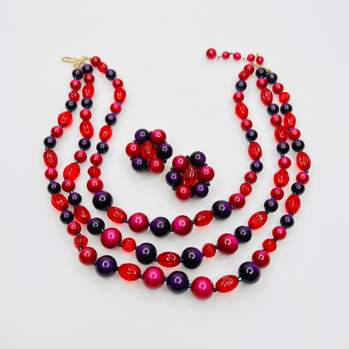 Vintage Marvella triple strand necklace and clip earrings with purple pink moonglow and translucent red beads.
