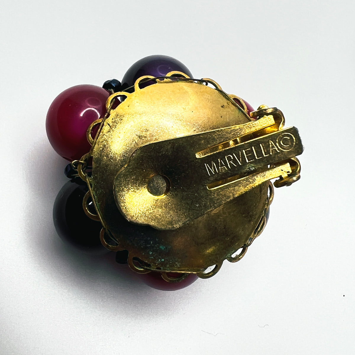 Close-up of MARVELLA signed gold-tone clip-on earring backing on vintage 1950s jewelry.