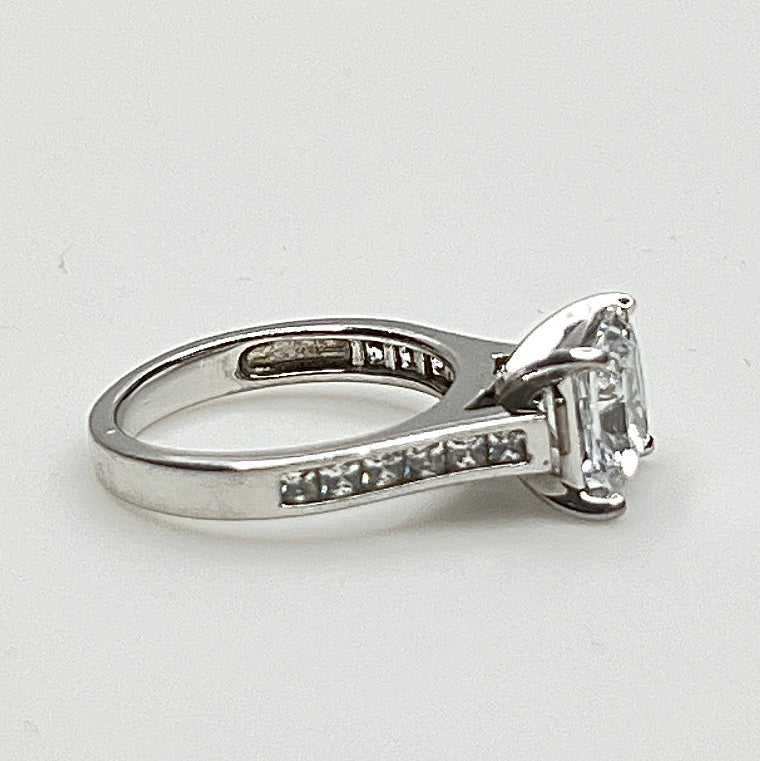 CZ ring with a large central stone and smaller stones on a light gray background