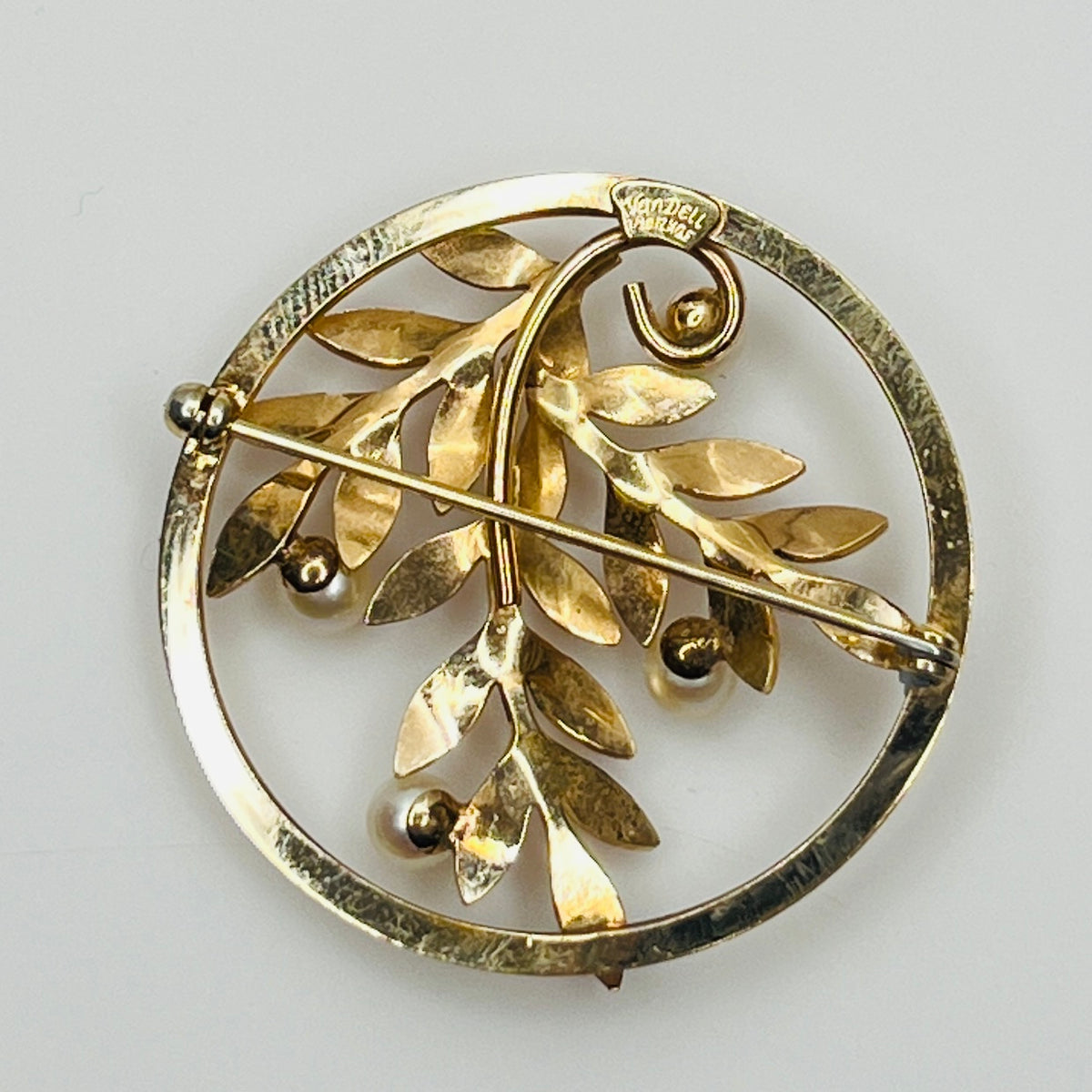 Close-up of brooch with textured gold leaves and five pearls
