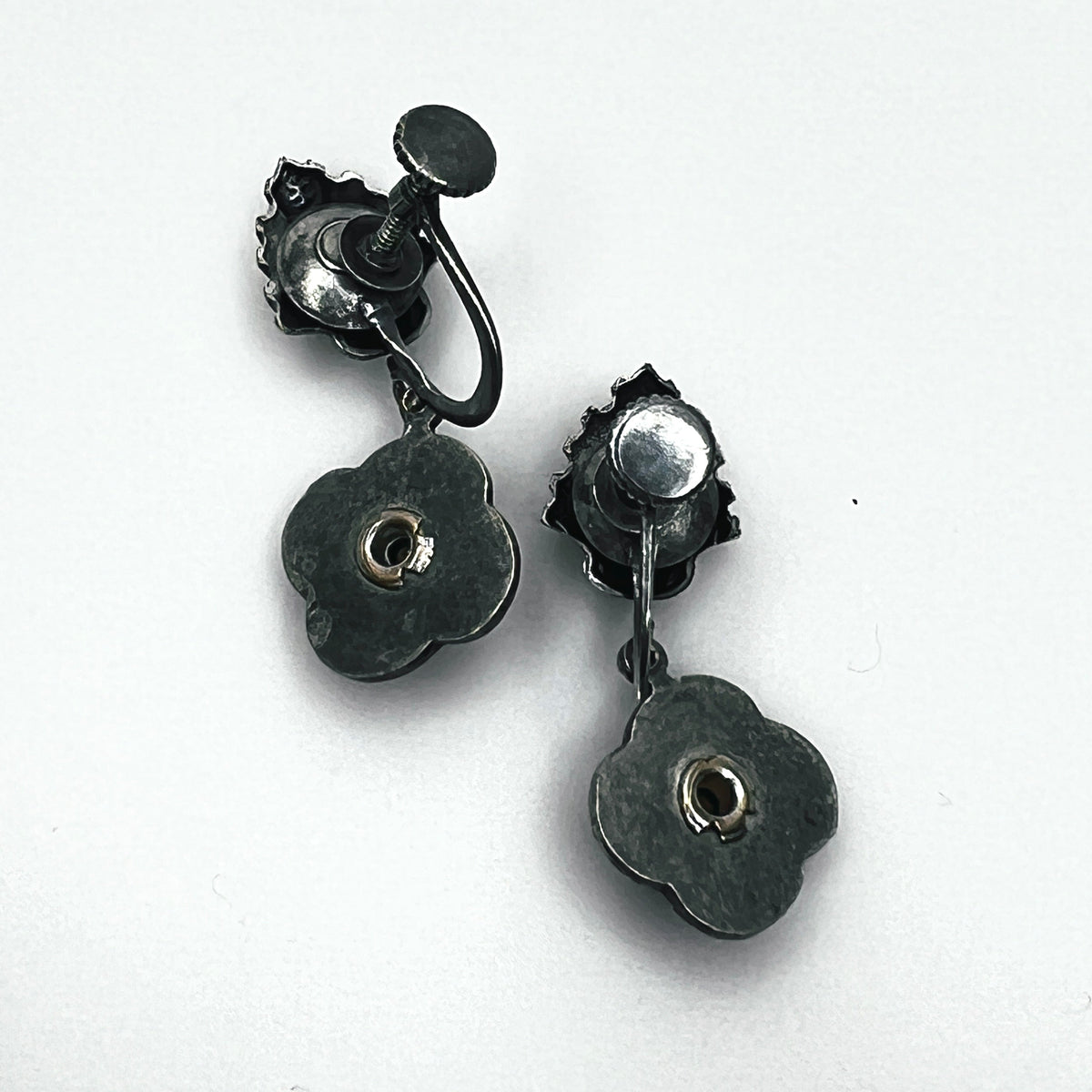 Reverse of vintage screw-back floral earrings showing adjustable screw fittings and metal construction.