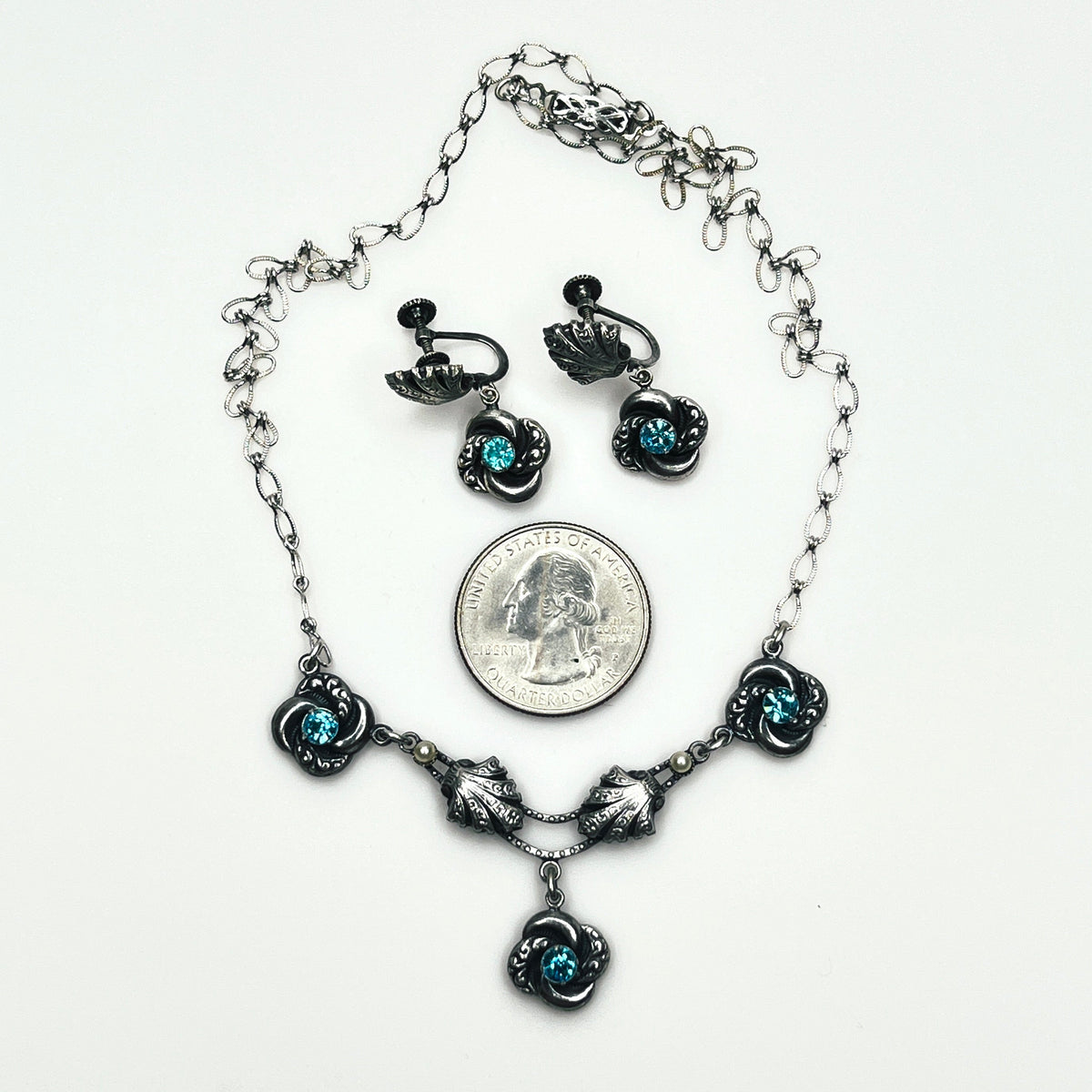 Vintage aqua rhinestone necklace and matching screw-back earrings displayed with quarter for size comparison.