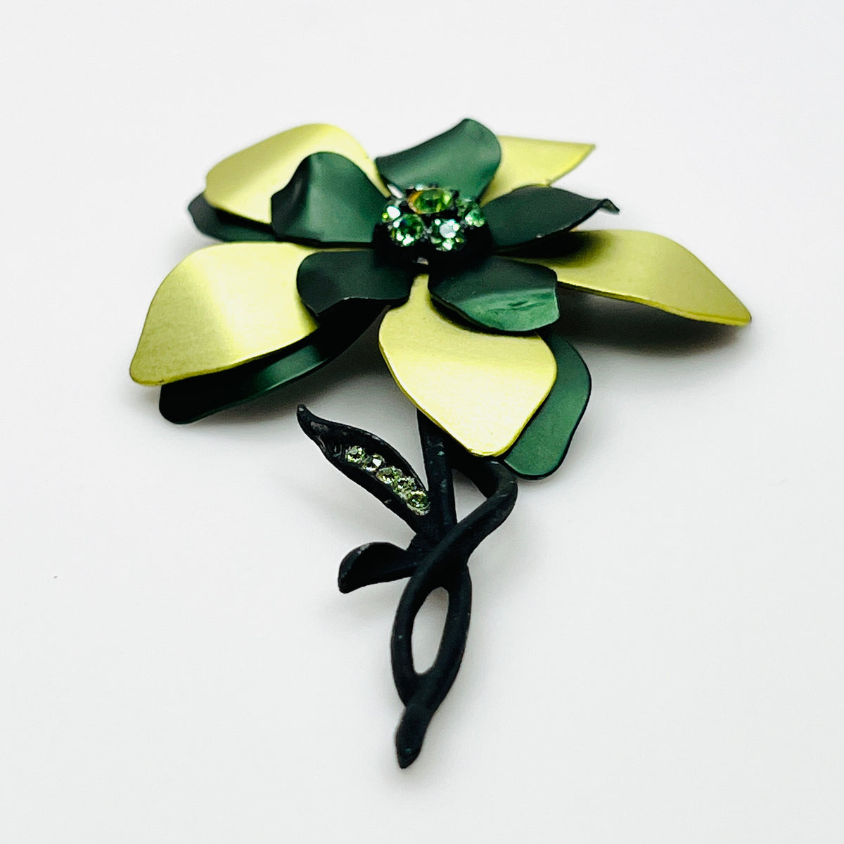 Side view of vintage 1970s green enamel flower brooch showing curved layered petals, rhinestone center, and dimensional construction.