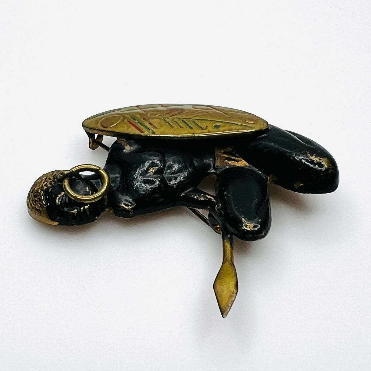 Side view of vintage African figural brooch highlighting dimensional metalwork and colorful shield details.