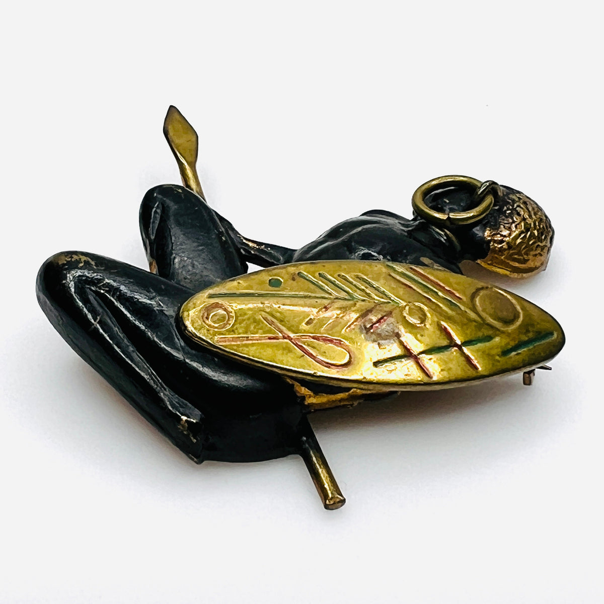 Side view of vintage African figural brooch highlighting dimensional metalwork and colorful shield details.