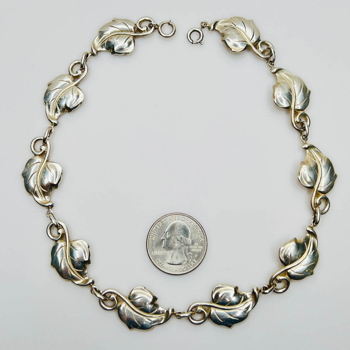 Linked leaf motif sterling necklace flat lay with coin for scale