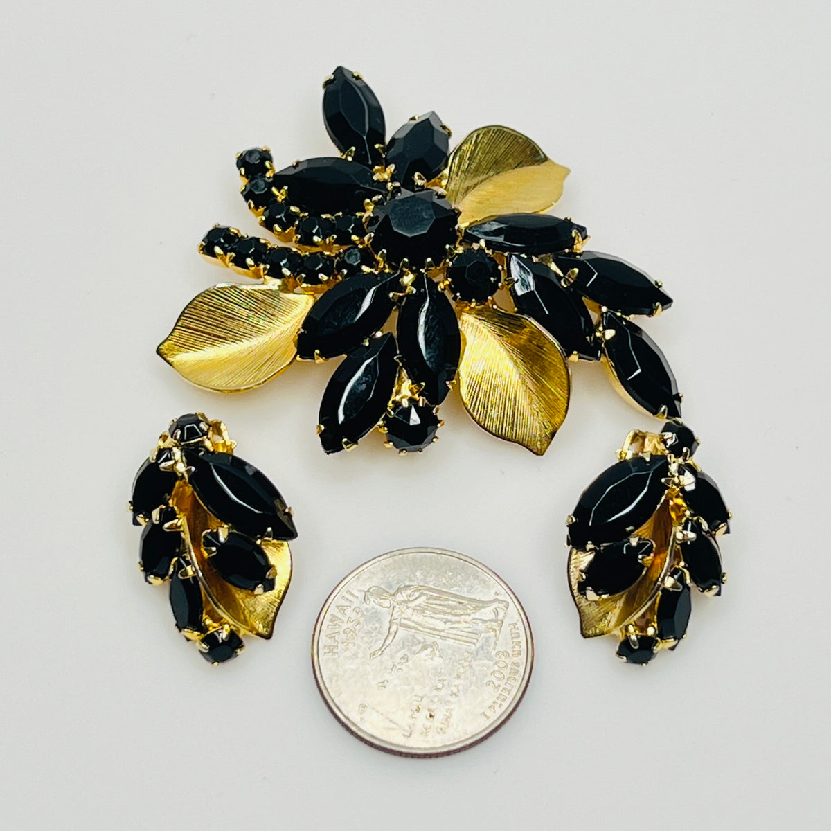 Close-up of Weiss signed black rhinestone clip-on earrings with gold leaf accents