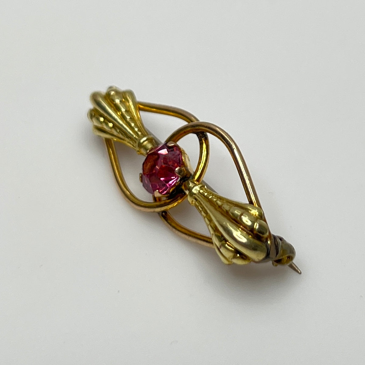 Vintage estate brooch with scroll design and prong-set pink glass stone