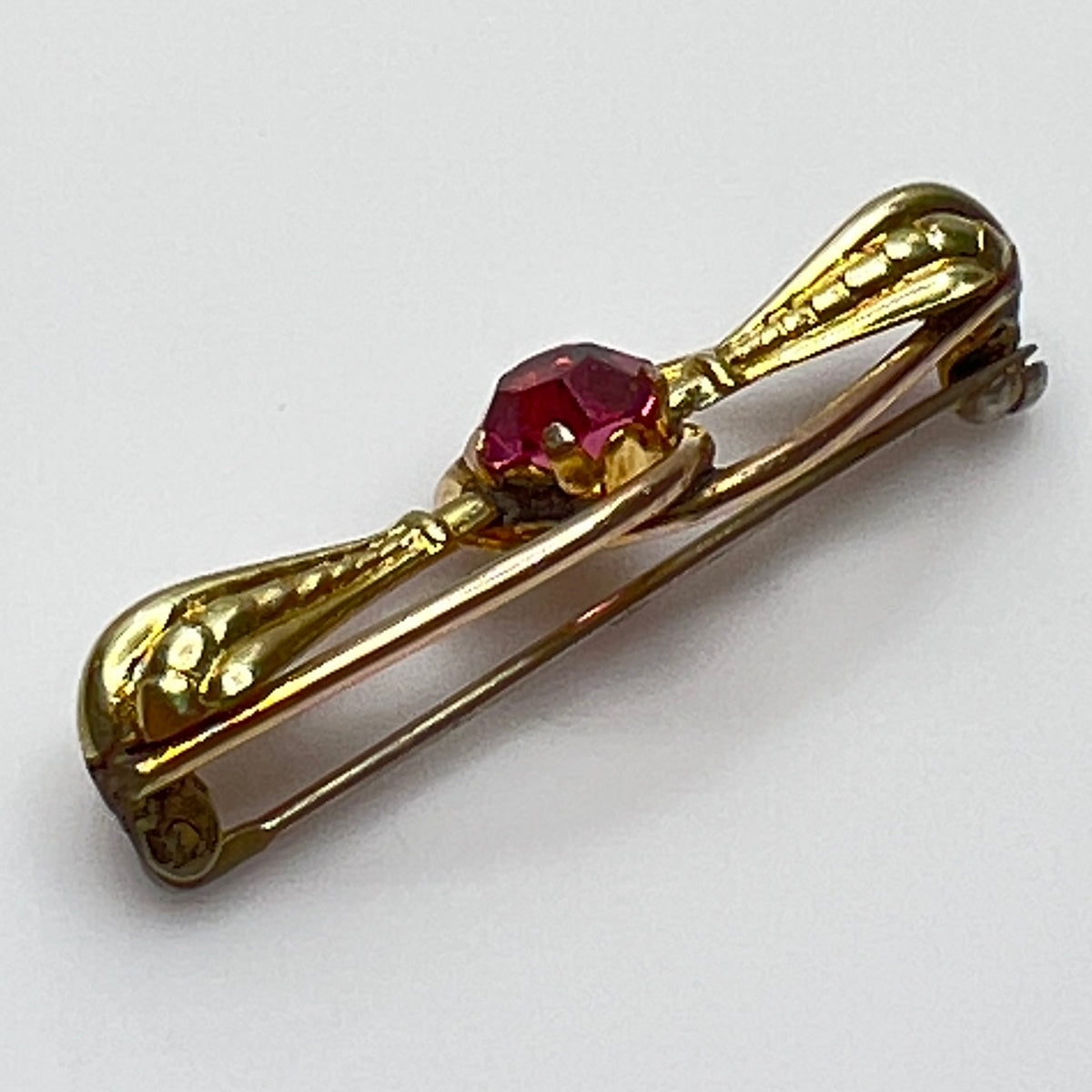 Vintage estate brooch with scroll design and prong-set pink glass stone
