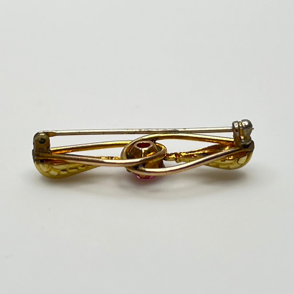 Vintage estate brooch with scroll design and prong-set pink glass stone