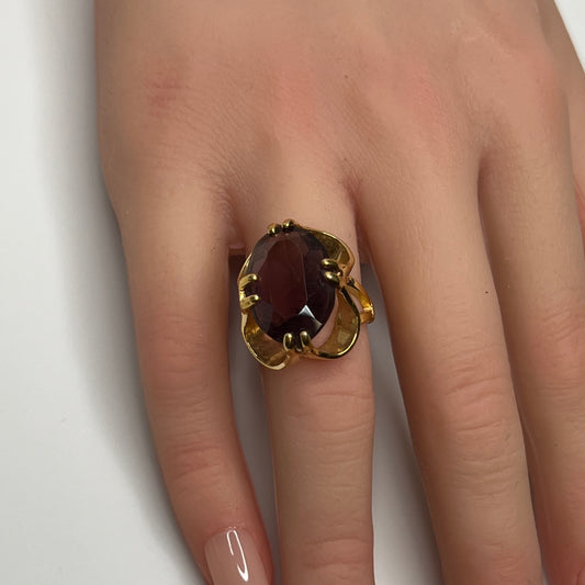 Bold 1970s gold-plated ring with large oval purple stone on hand