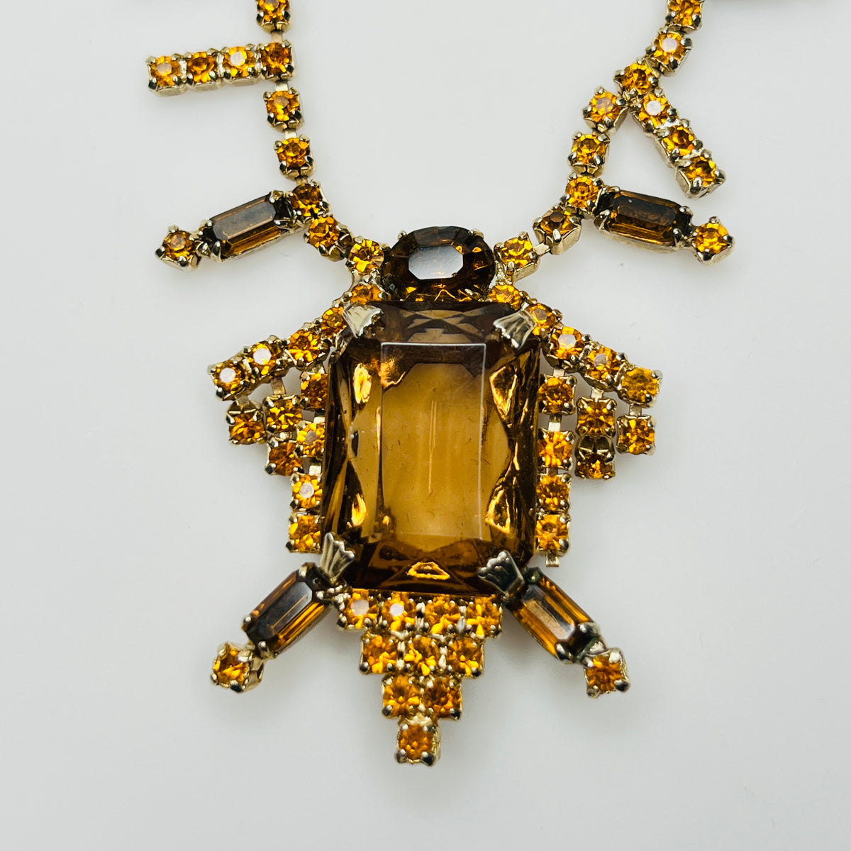 Close-up of emerald cut amber glass center stone with rhinestones